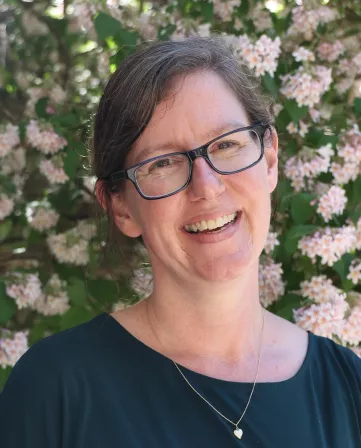 photograph of Dean Liz Derickson smiling and standing outside of Parrish Hall