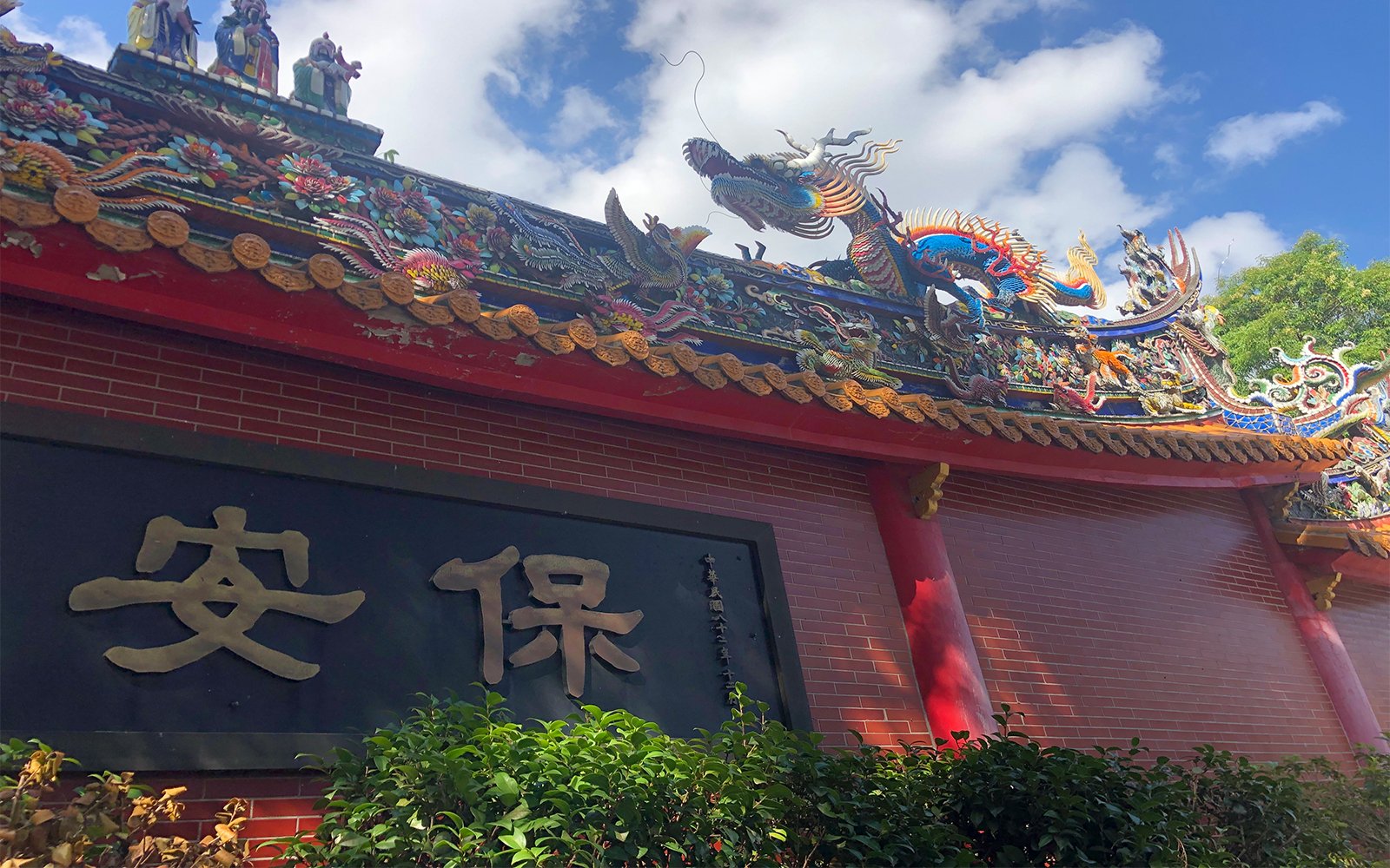 Colorful red brick wall with sculptures of dragon and people on roof