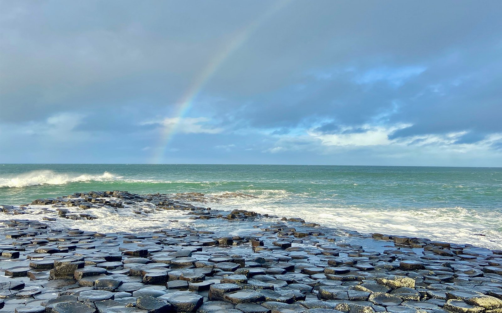 Rainbow over beach covered by circular stones