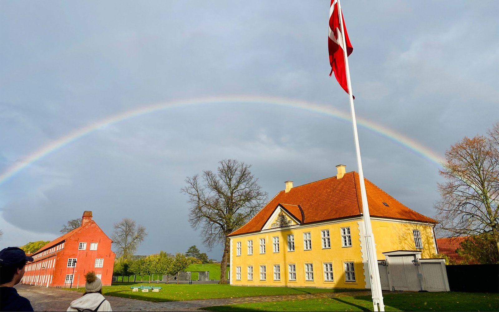 Rainbow over houses with flag in foreground