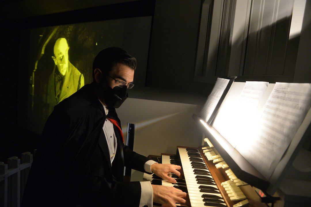 Person wearing mask plays organ during movie screening