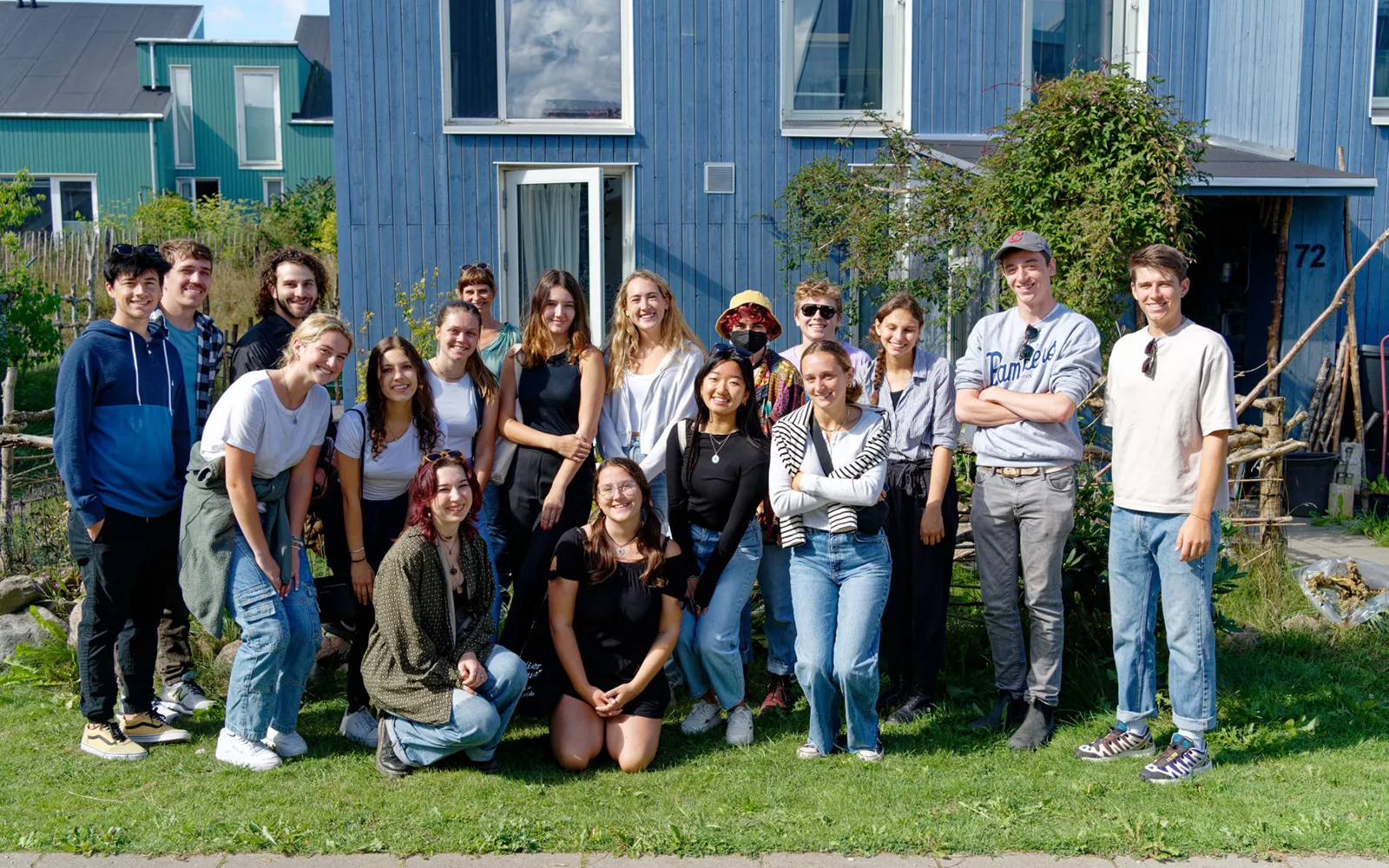 Group of students smiling in front of blue building