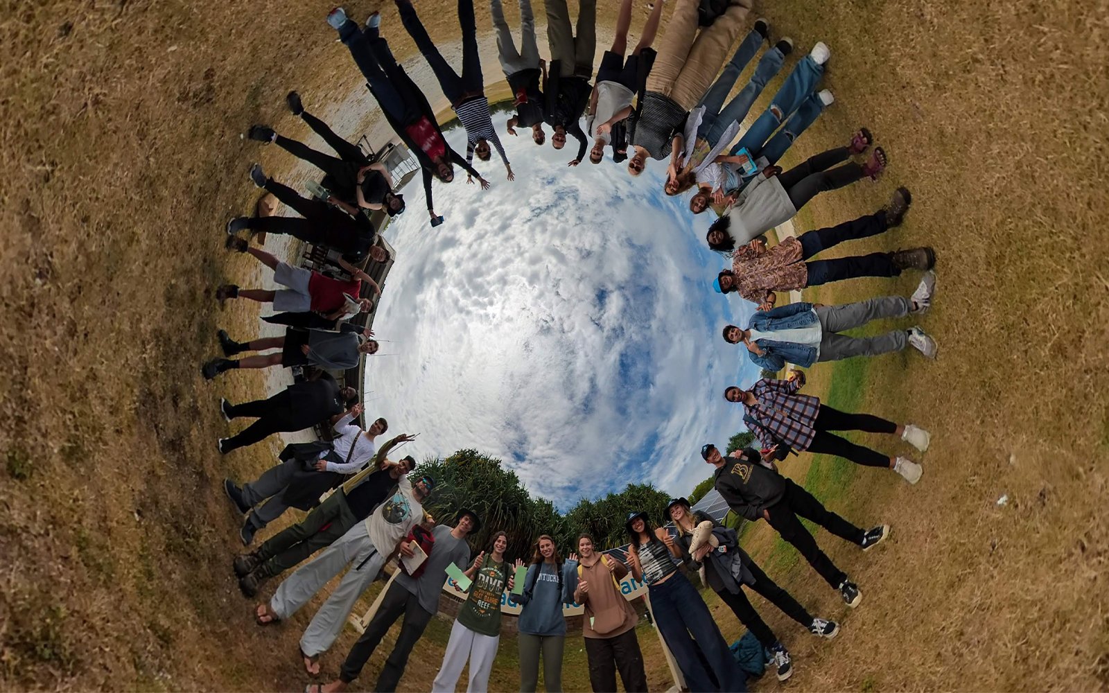 Group photo of students (edited so that students are in a circle facing inward with the sky at the center)