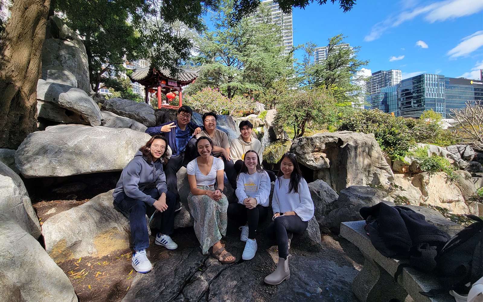 Group of students sitting on rocks with shrine and city in background