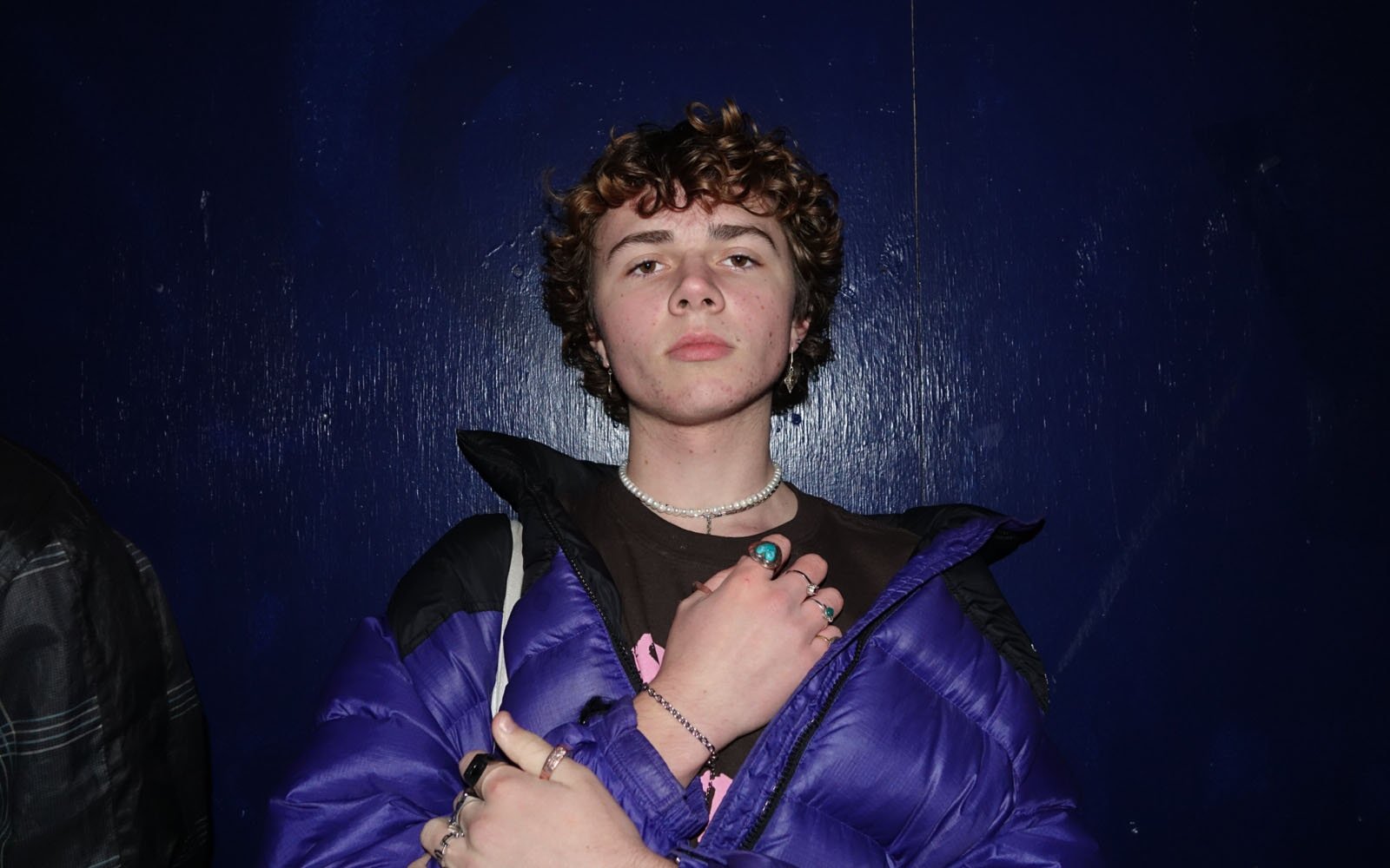 Young person with blue jacket and many rings