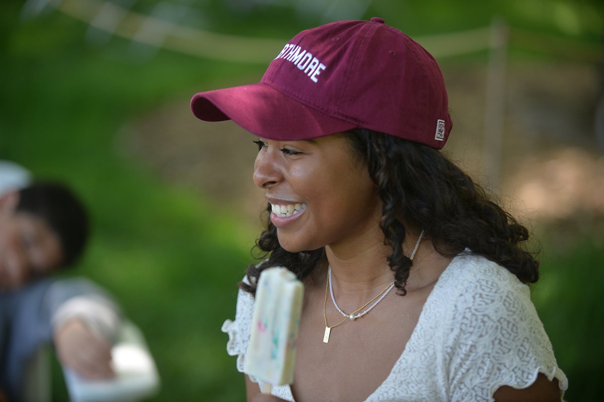 Person wearing Swarthmore hat enjoys popsicle outdoors