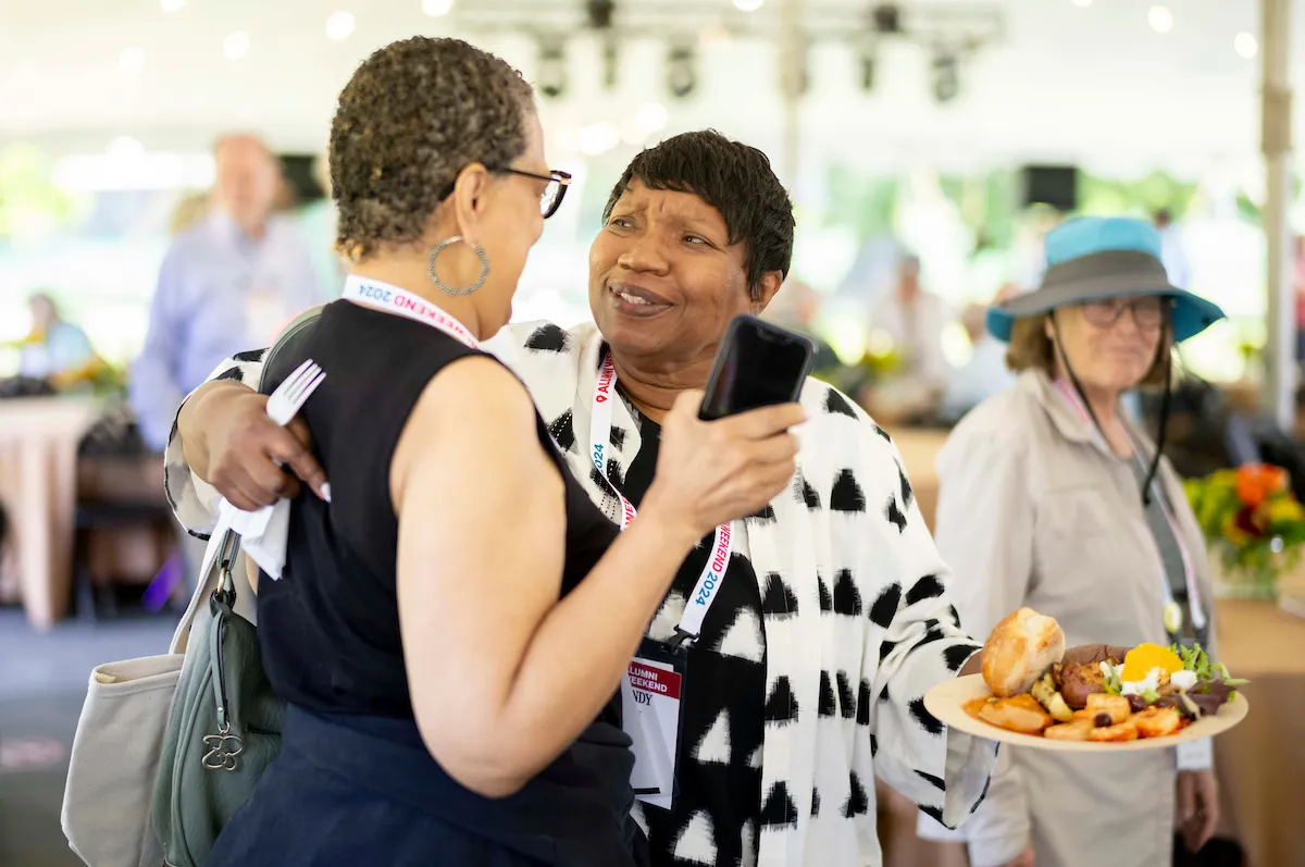 Alumni hug at outdoor reception