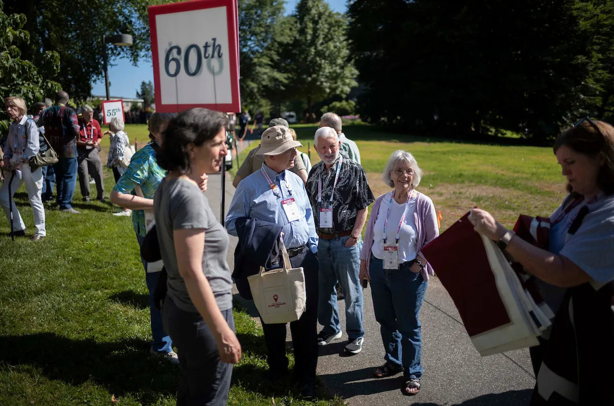 Alumni stand next to flag reading "60th" for Parade of Classes