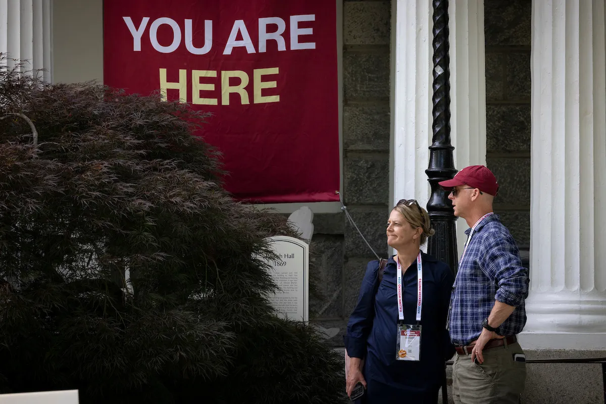 Alumni stand next to banner that reads "You Are Here"