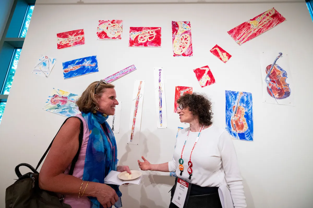 Two alumni have conversation in front of art at List Gallery