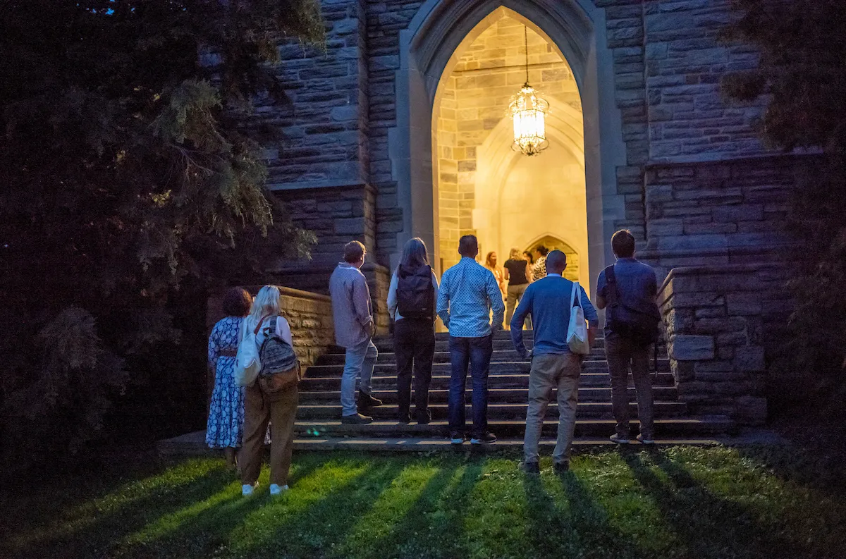 Alumni stand by clothier belltower alcove at night