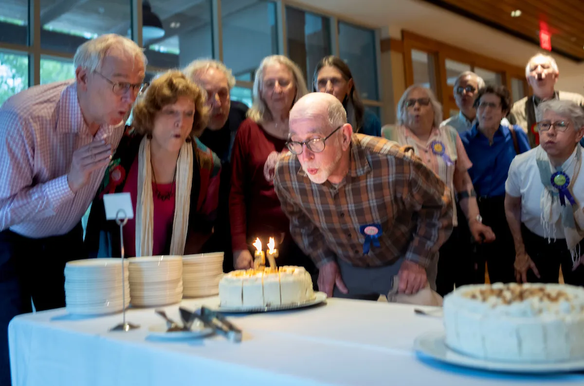 Group of alums blow out candles on cake