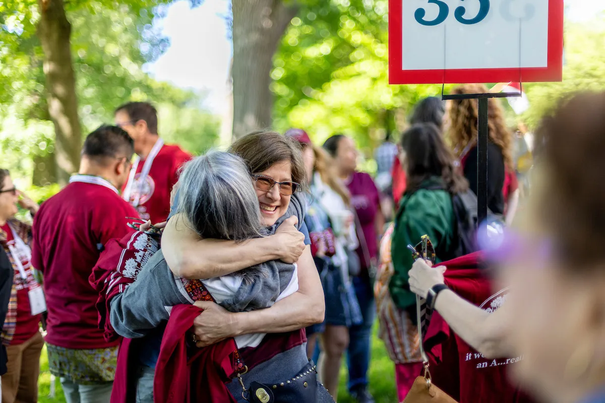 Person hugs at other alum at Parade of Classes