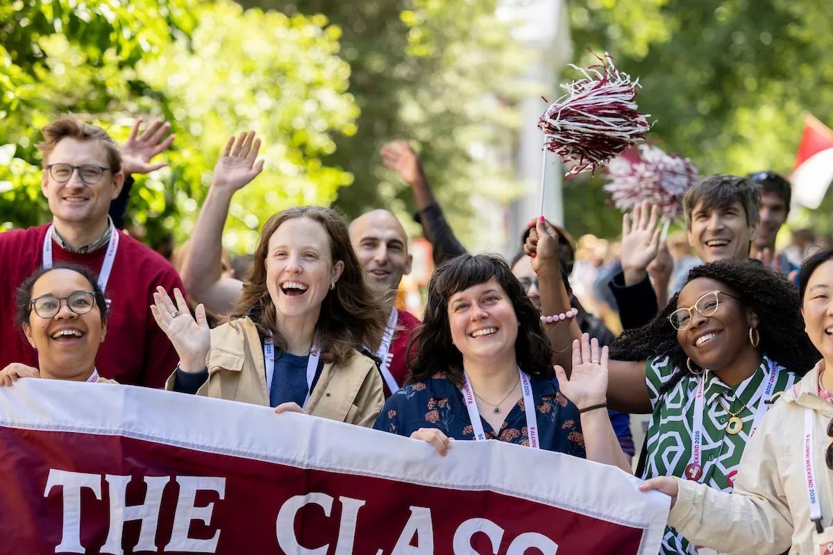 Alumni holding up class banner wave at parade of classes