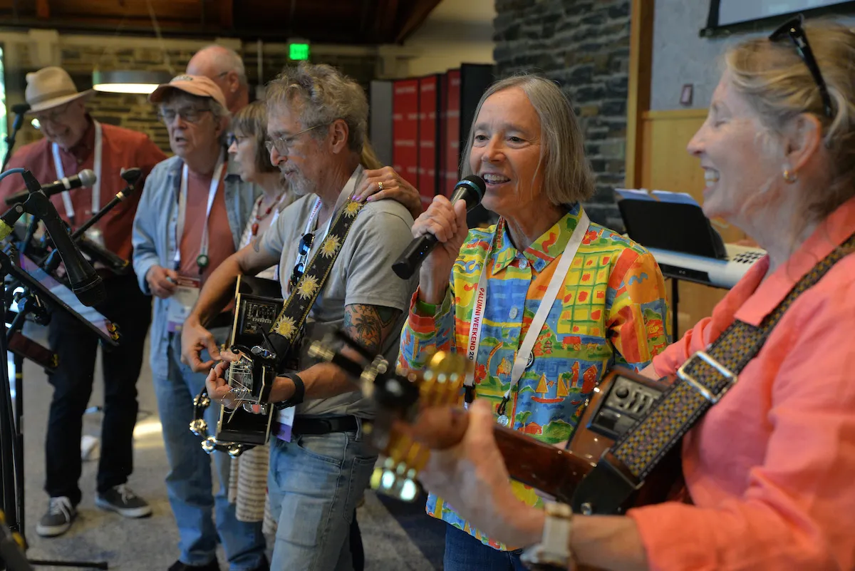 Group of alumni play instruments and sing into microphones