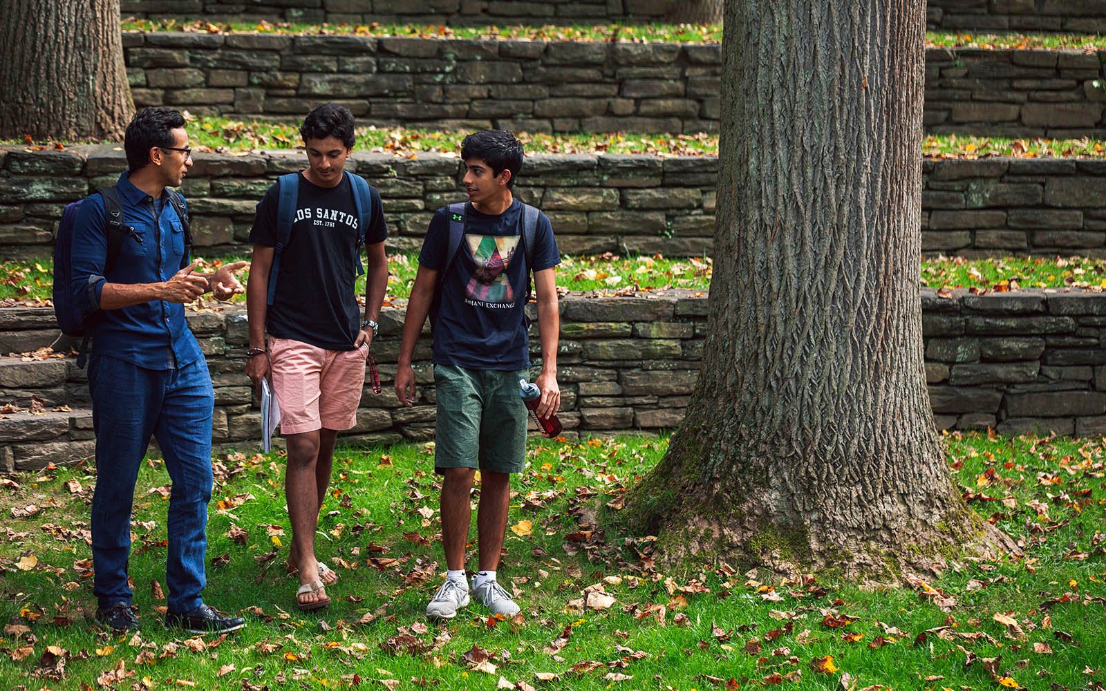 Faculty and two students talking in amphitheater 