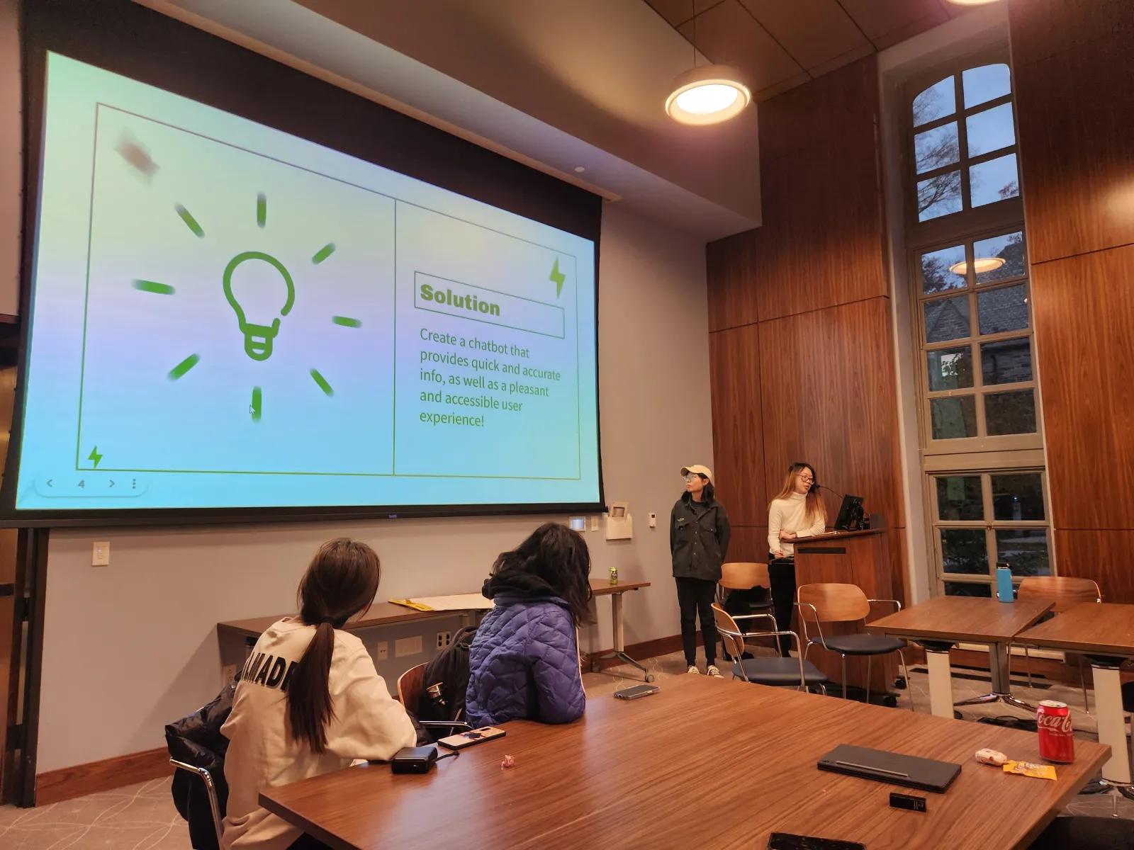 Student team giving their pitch with their slideshow behind them