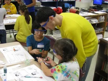 Two local third-graders are showing a Swarthmore sudent the polymer they created