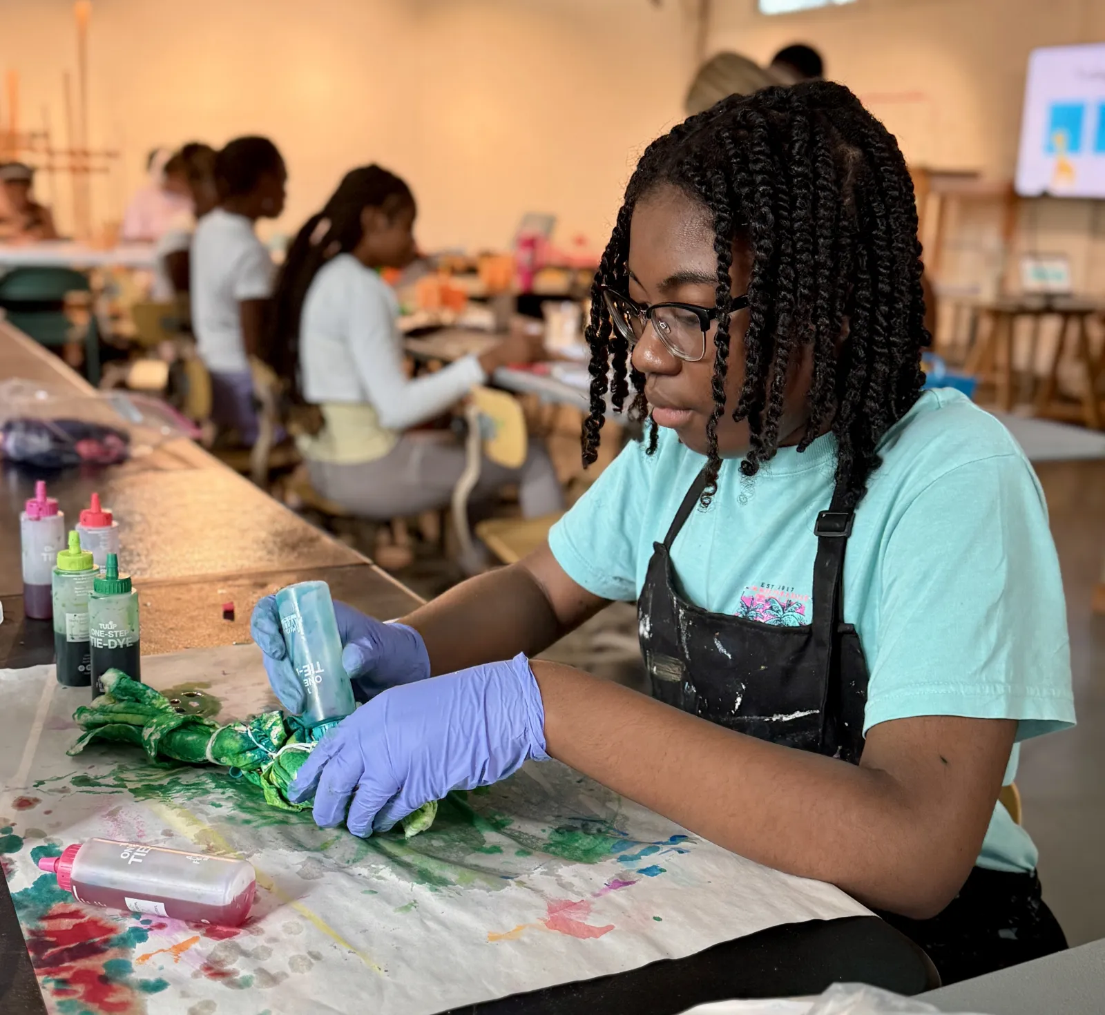 a high school girl dyes fabric in an art studio