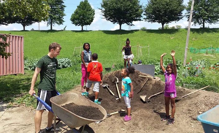 A student works with children on the farm