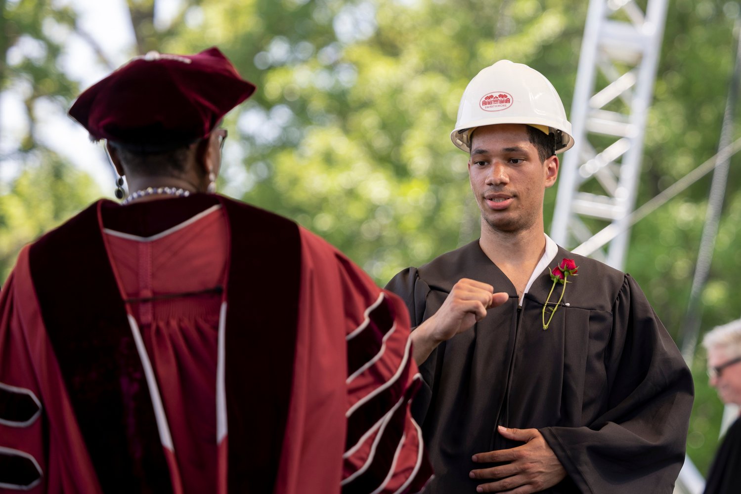 Student wearing hard hat elbow bumps president smith
