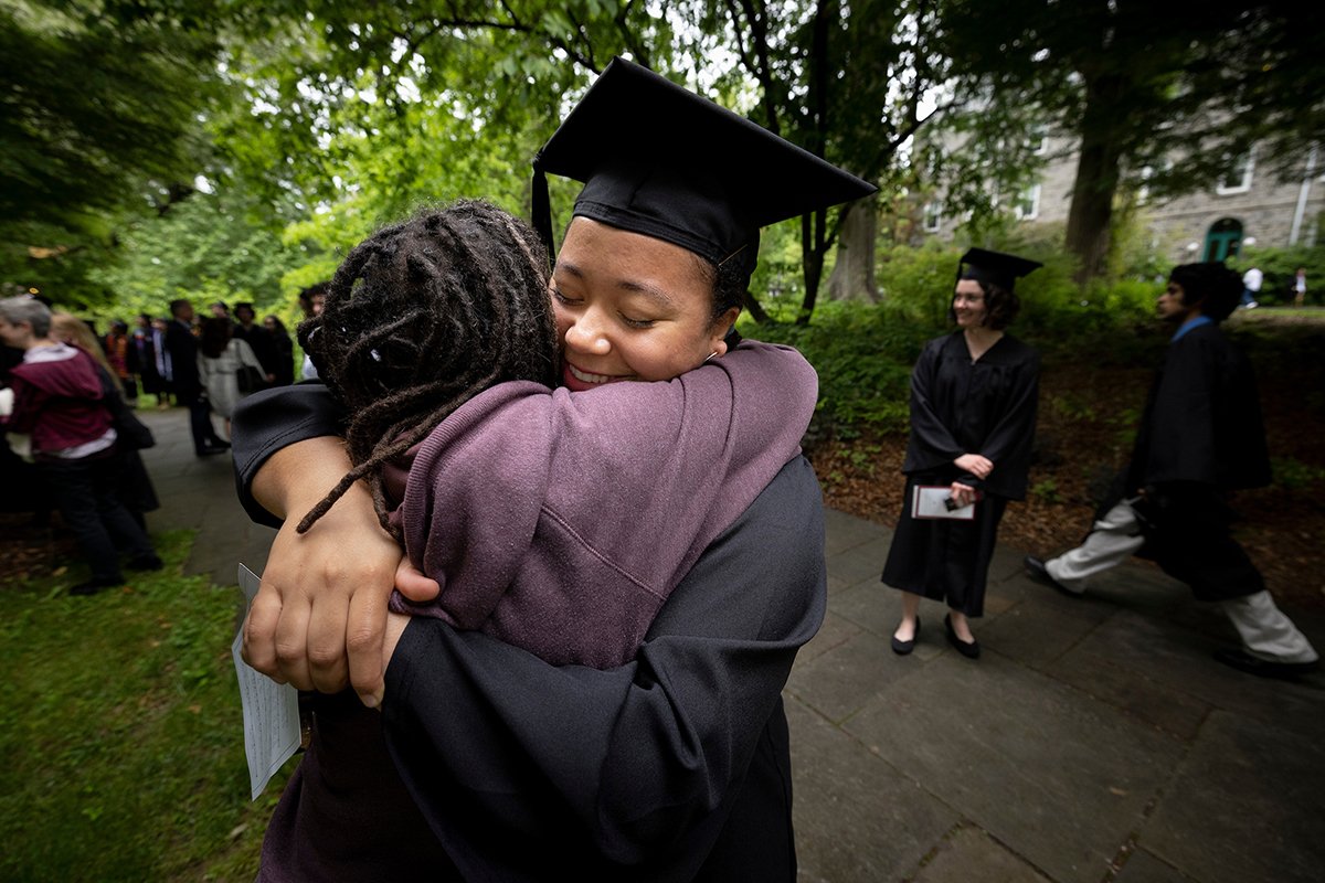 Student wearing cap and gown hugs