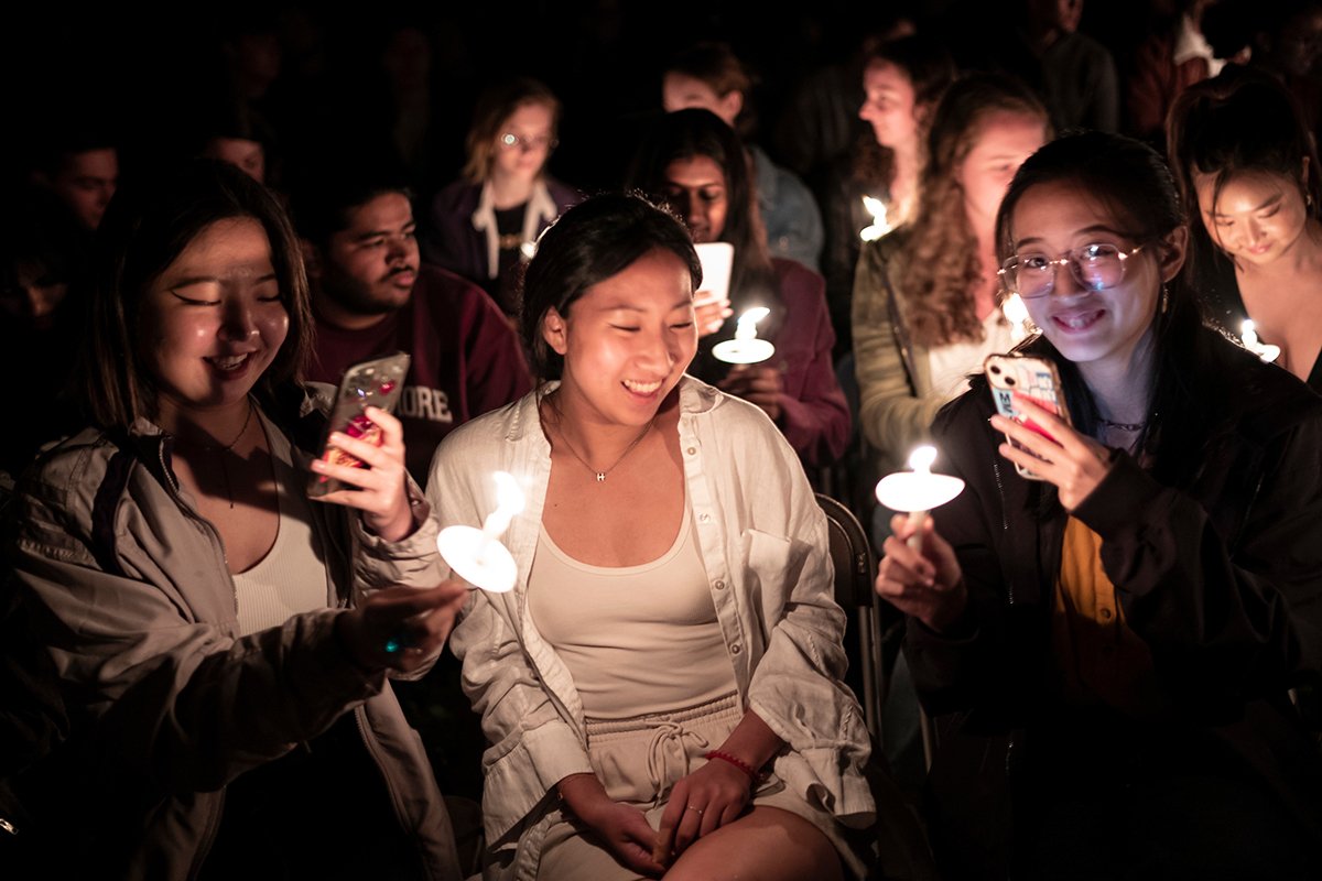 Students hold candles at night