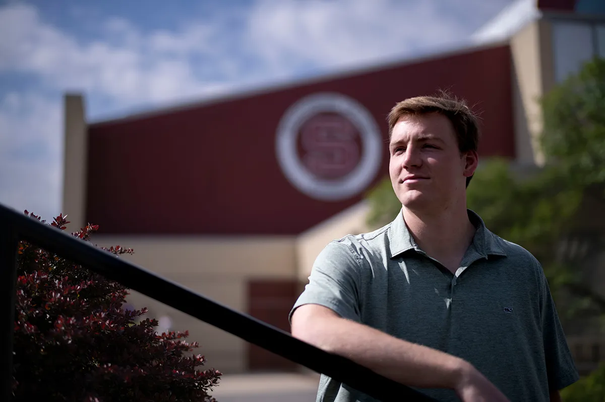 Michael Caprise outside building with Swarthmore "S" logo