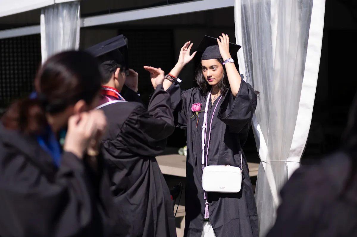 Students make last-minute adjustments to commencement regalia