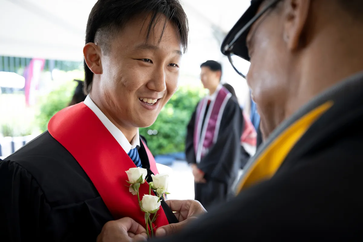 Student receives rose on commencement lapel