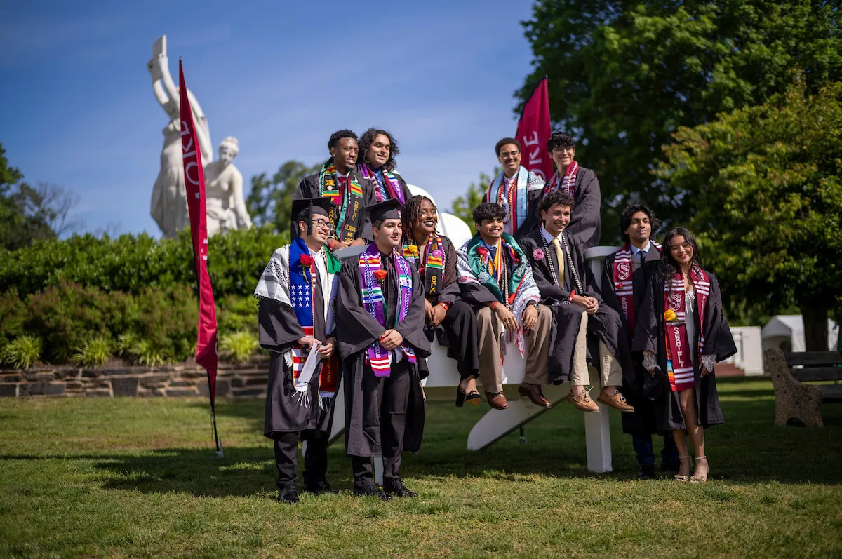 Students pose on big chair before commencement ceremony
