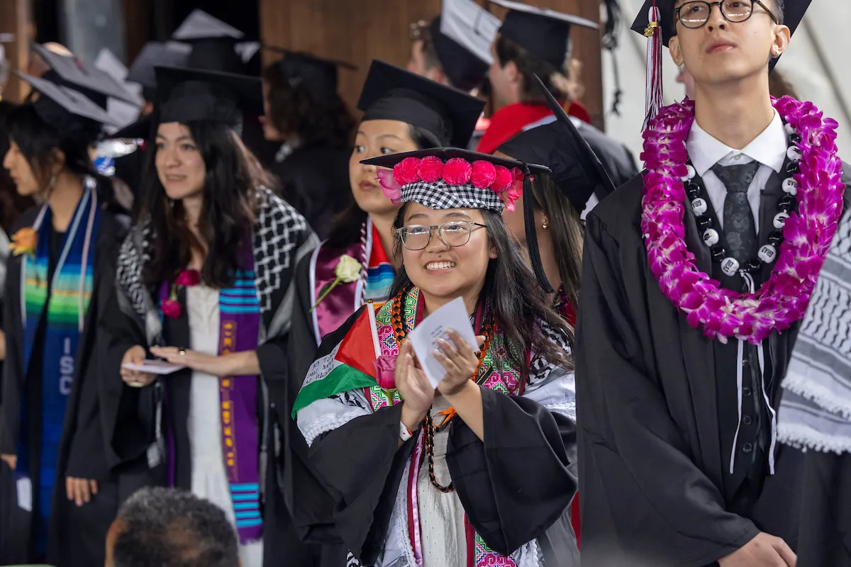 Students at commencement clap before getting on stage