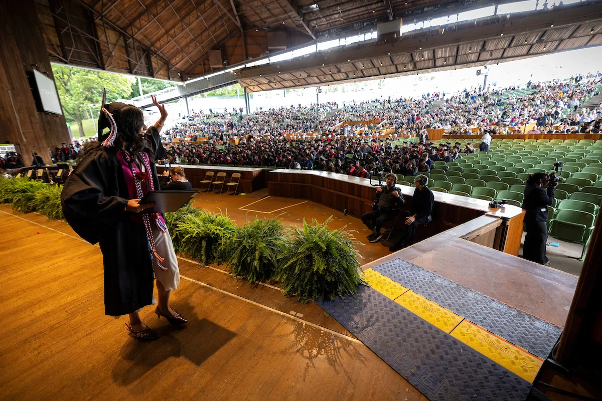 Student waves walking across stage after receiving diploma