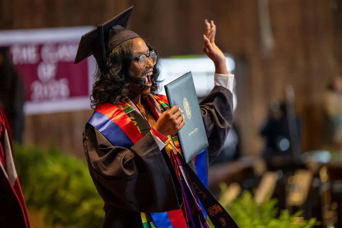 Student receives diploma and waves to crowd