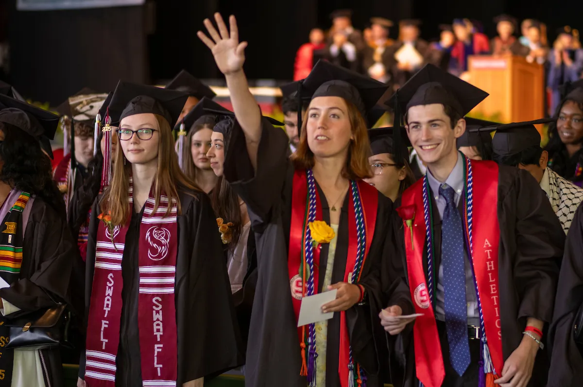 Students wave at crowd during commencement
