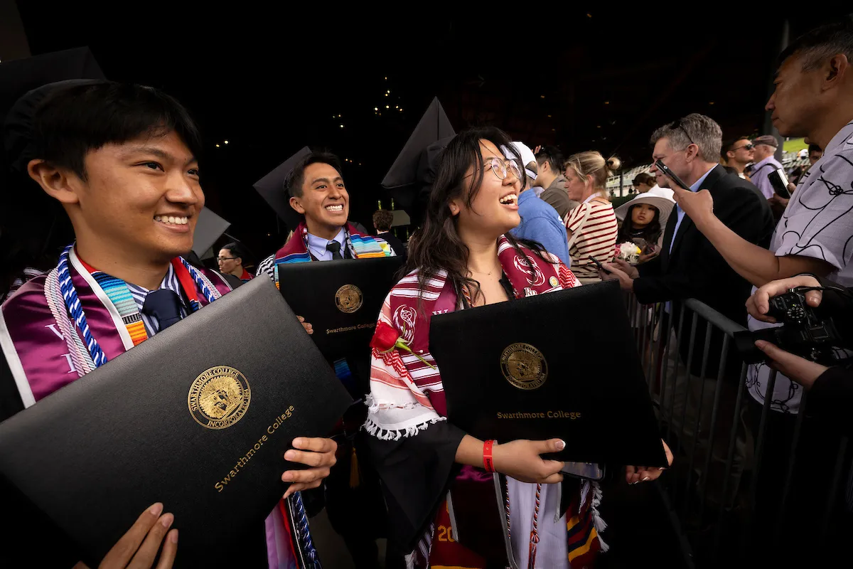 Students hold up diplomas after commencement