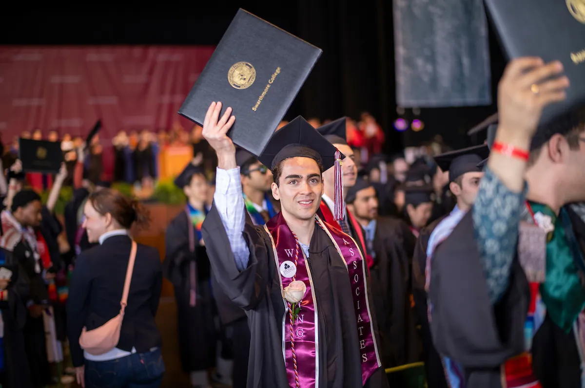 Students hold up diplomas after commencement
