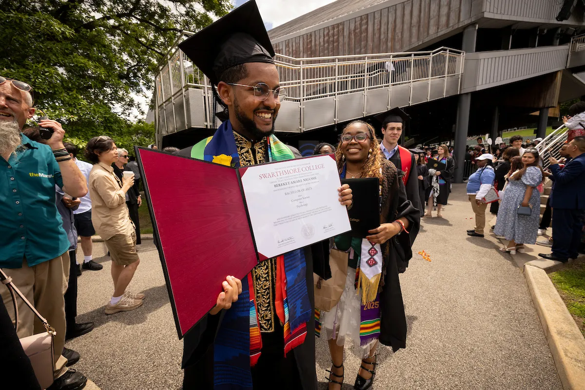 Student holds up diplomas after commencement