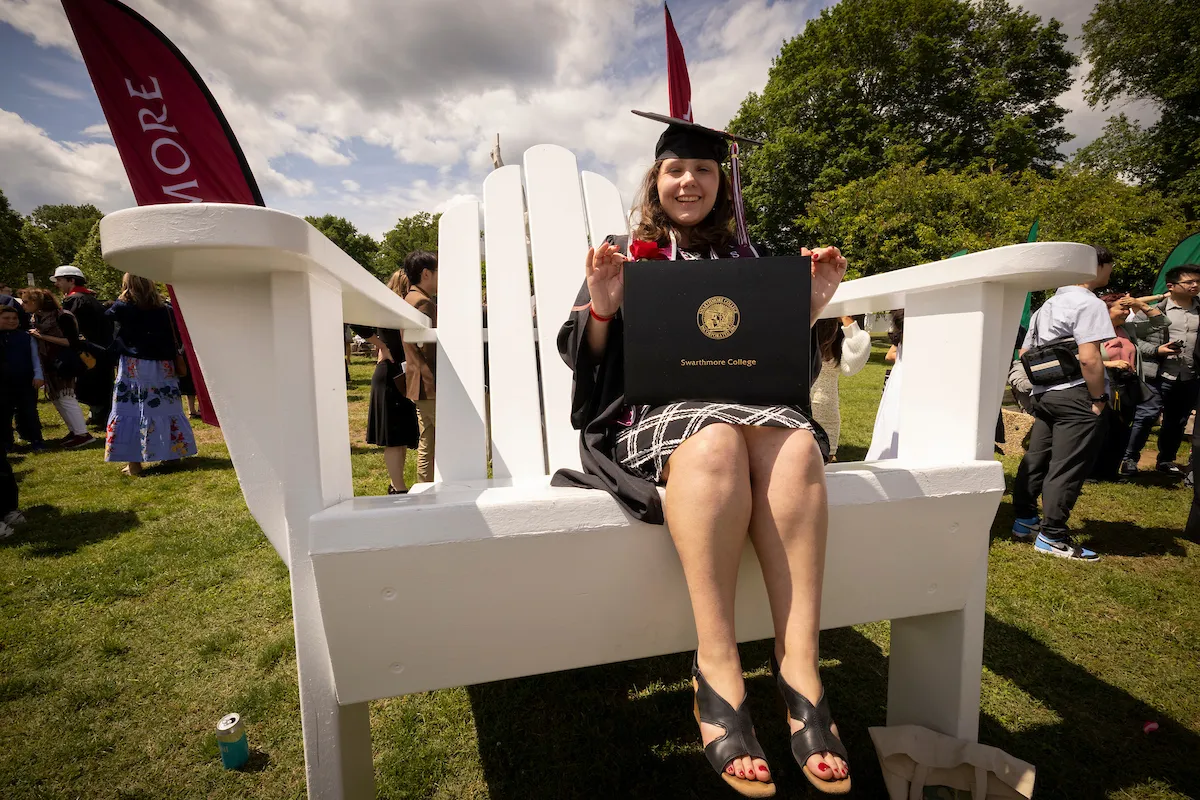 Student poses with diploma on big chair