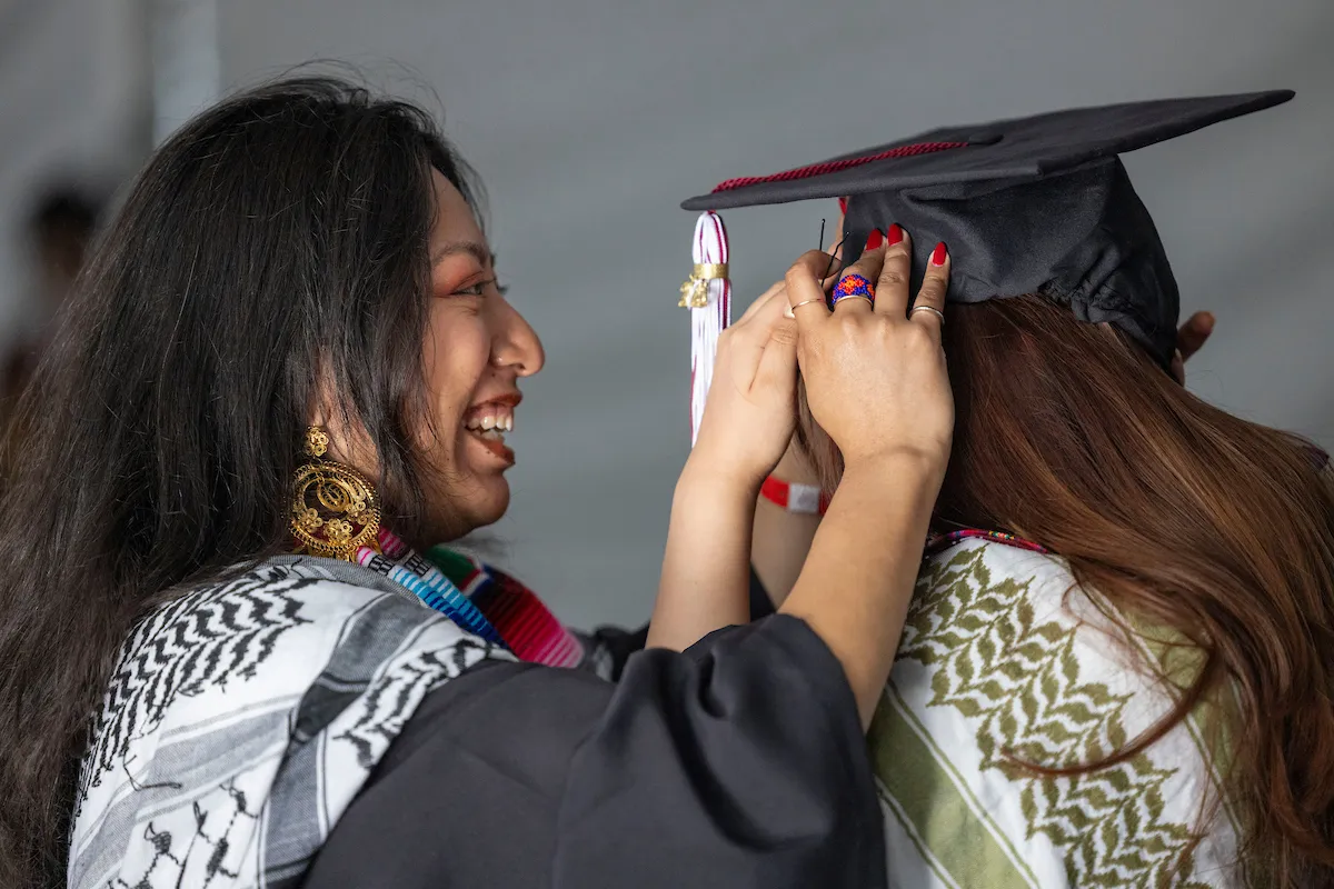 Student helps other student fix commencement mortarboard