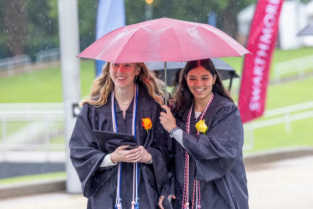 Students huddle under umbrella in rain