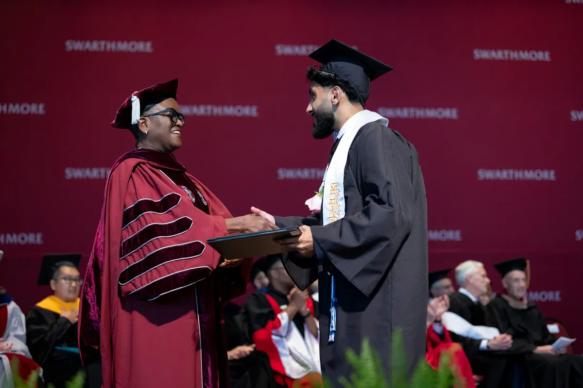 President Val Smith hands diploma to student