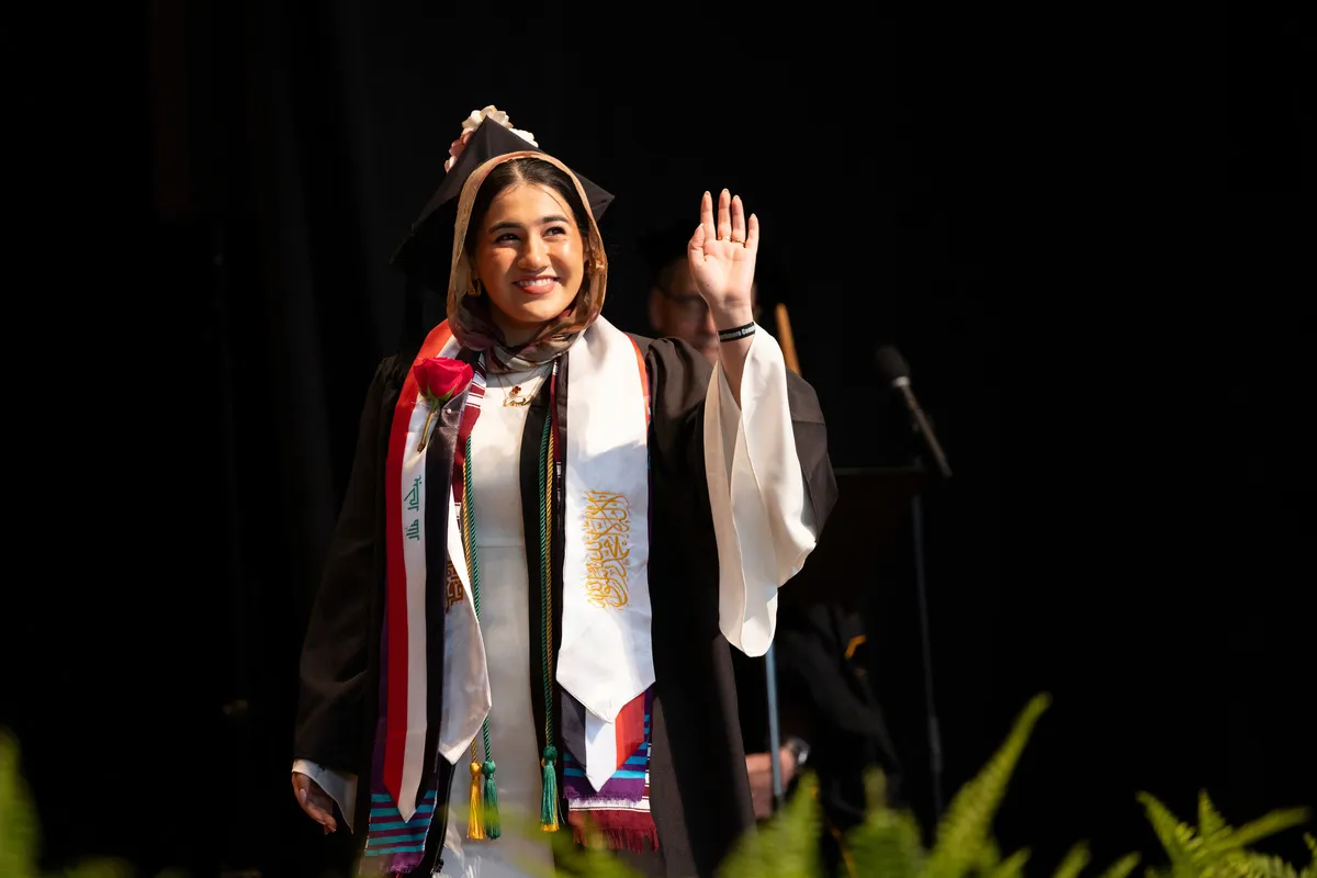 Student waves to crowd while walking to accept diploma