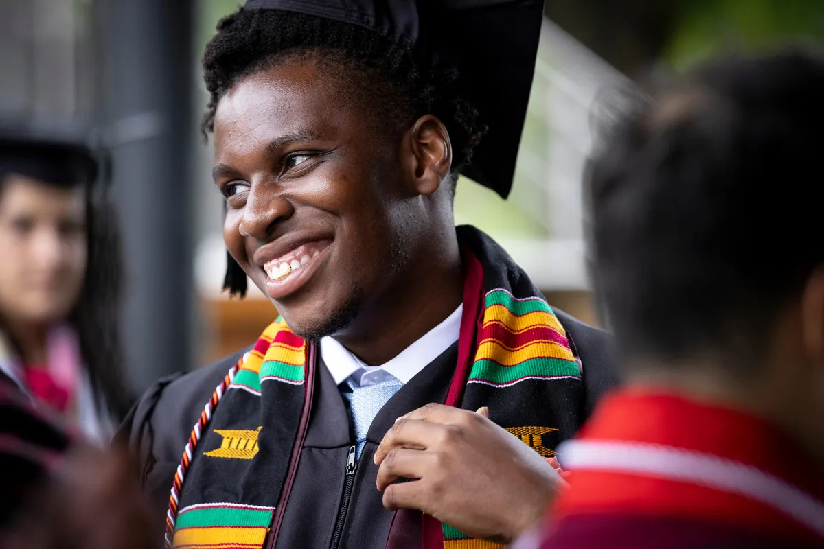 Student smiles while wearing commencement regalia