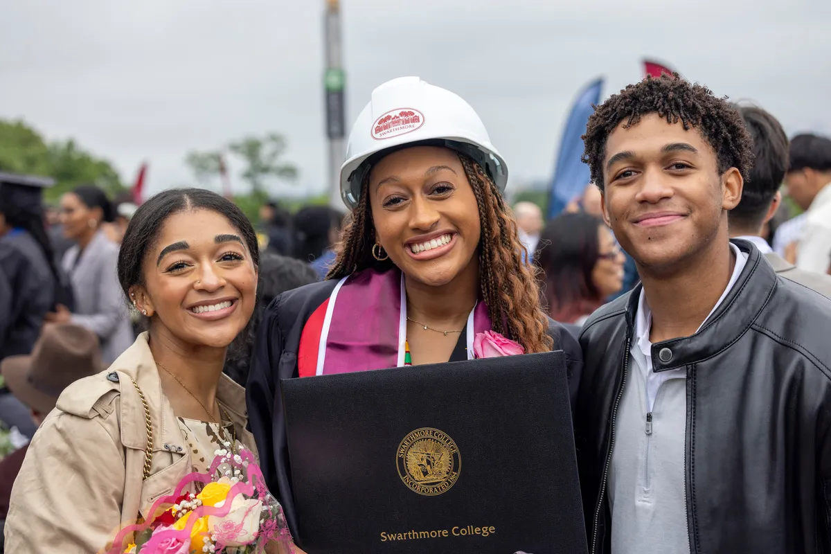 Student in white cibstruction helmet poses with family members