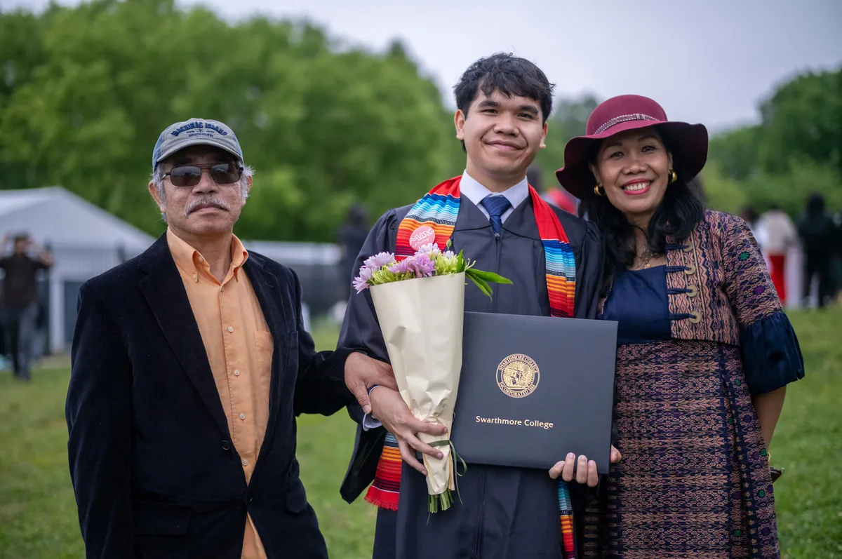 Student poses with family members while holding diploma