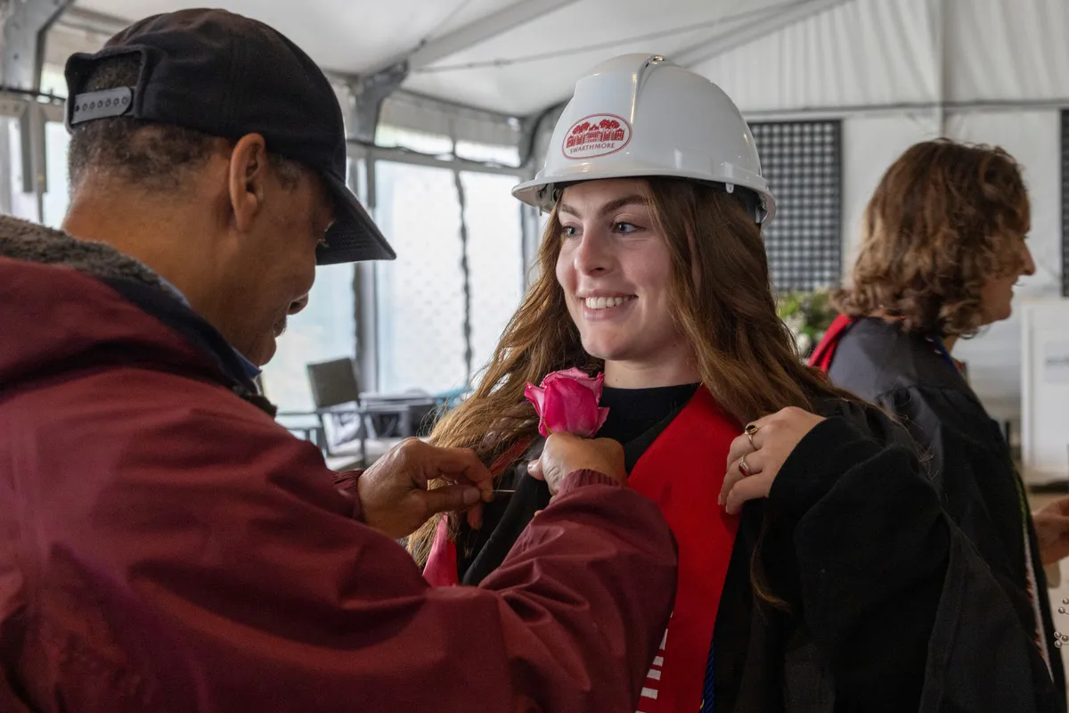 Person pins rose on student at graduation