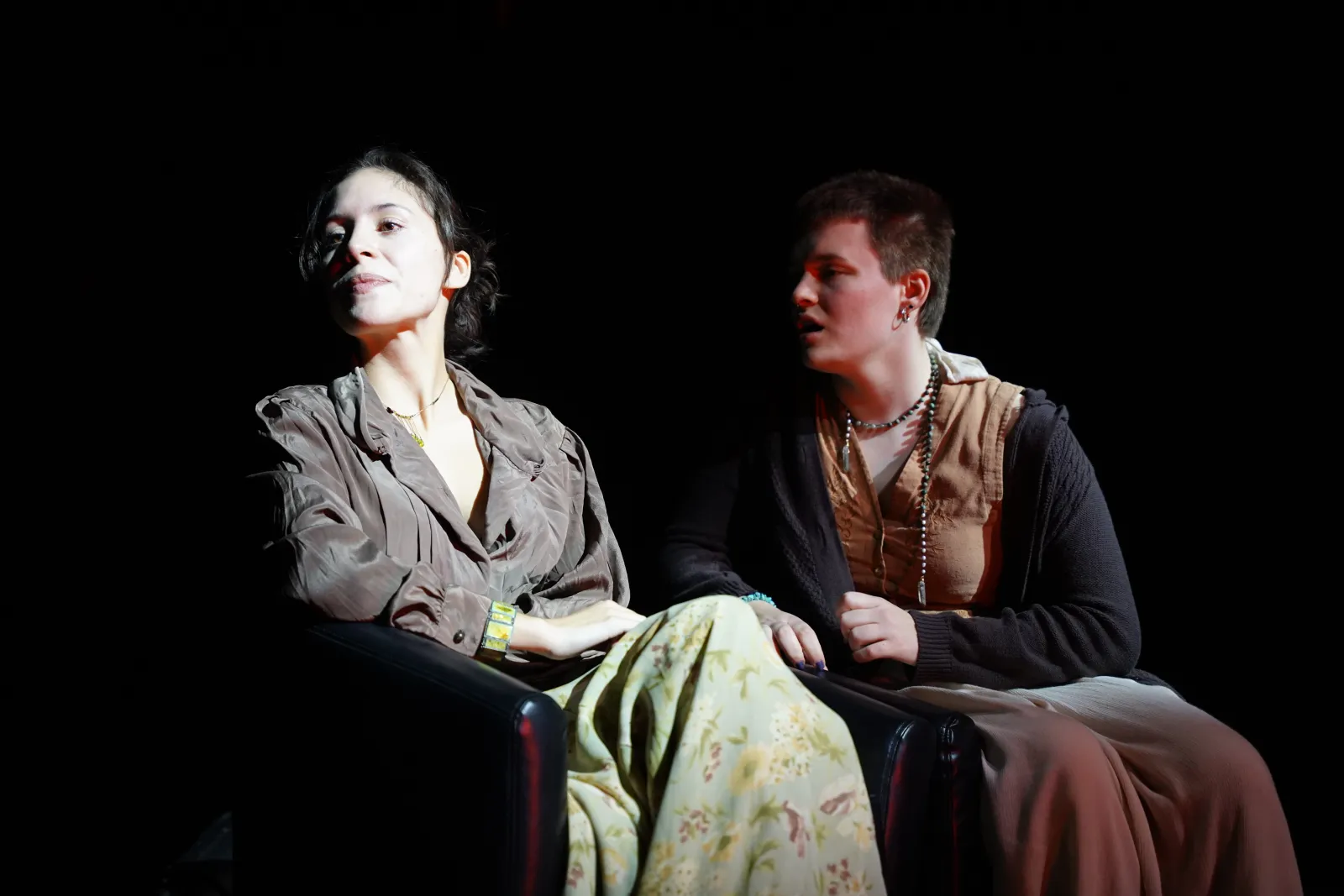 Two performers share a moment in an excerpt from Night of Scenes. One performer is illuminated by a spotlight and faces away from the other who makes a desperate face 