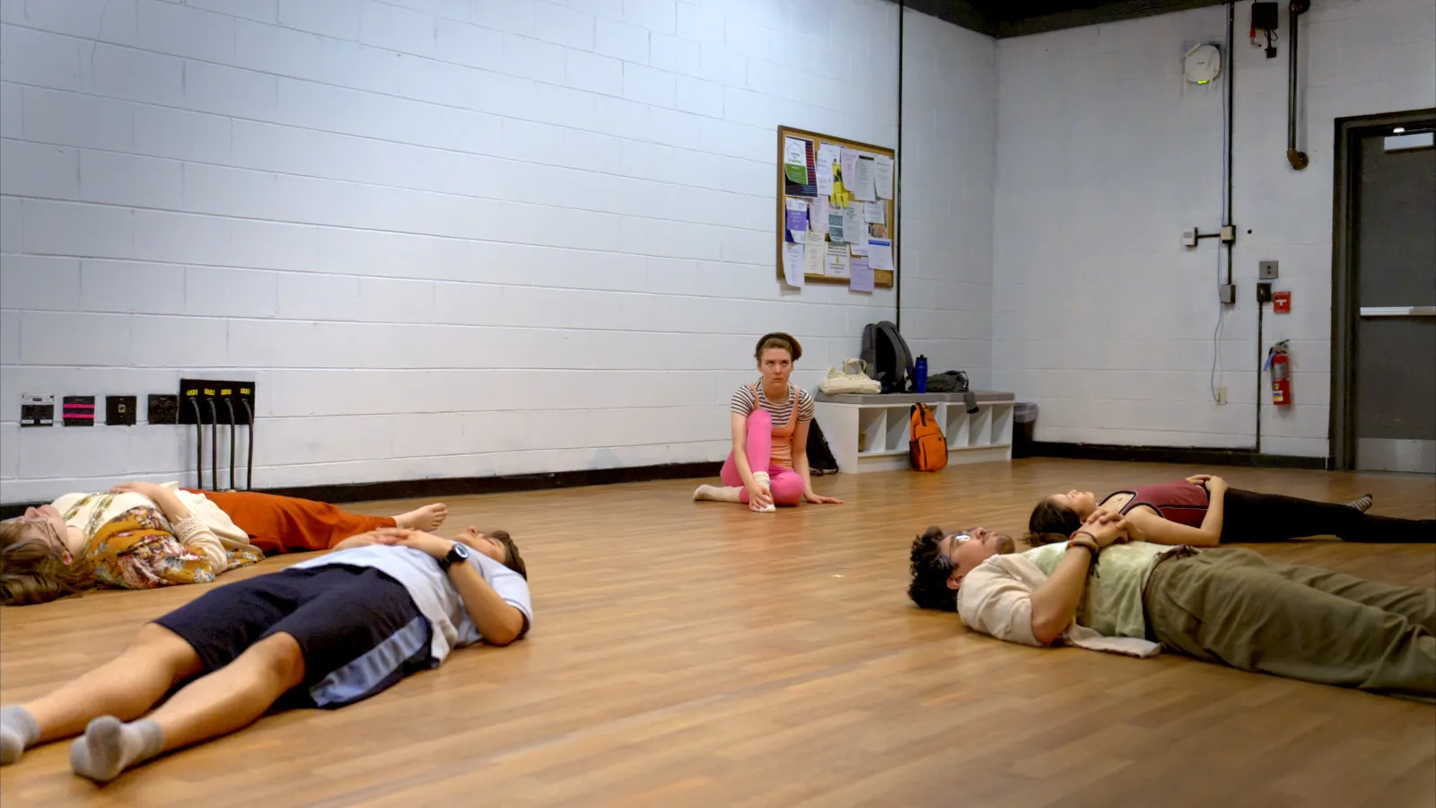 The students lie on the ground except for Lauren