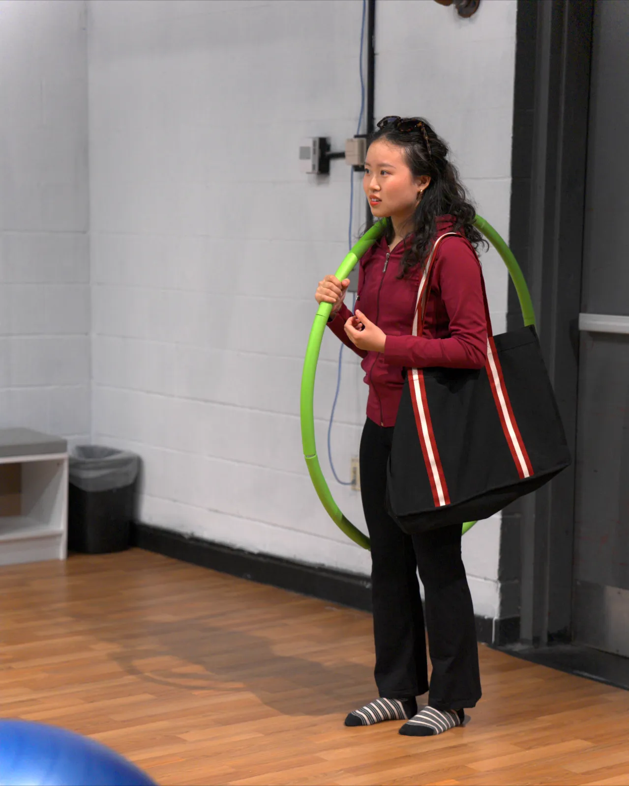 Theresa enters the studio with her hula hoop over her shoulder